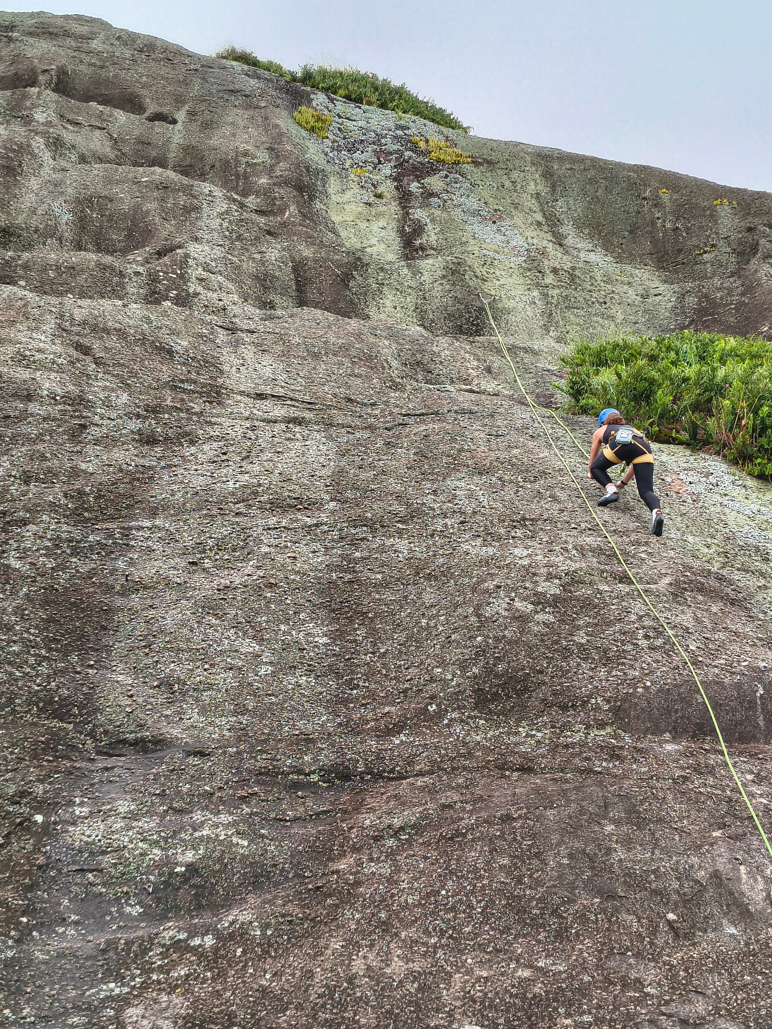 Aventureiros equipados com capacetes e baudriers na base das vias de escalada em Pedra Bela